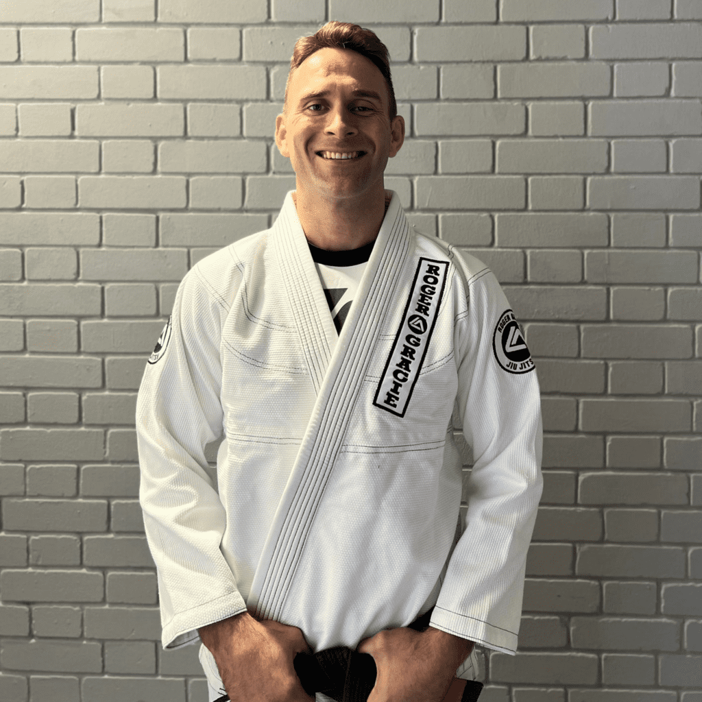 Black belt head coach and co-founder smiling at the camera in his Gi.